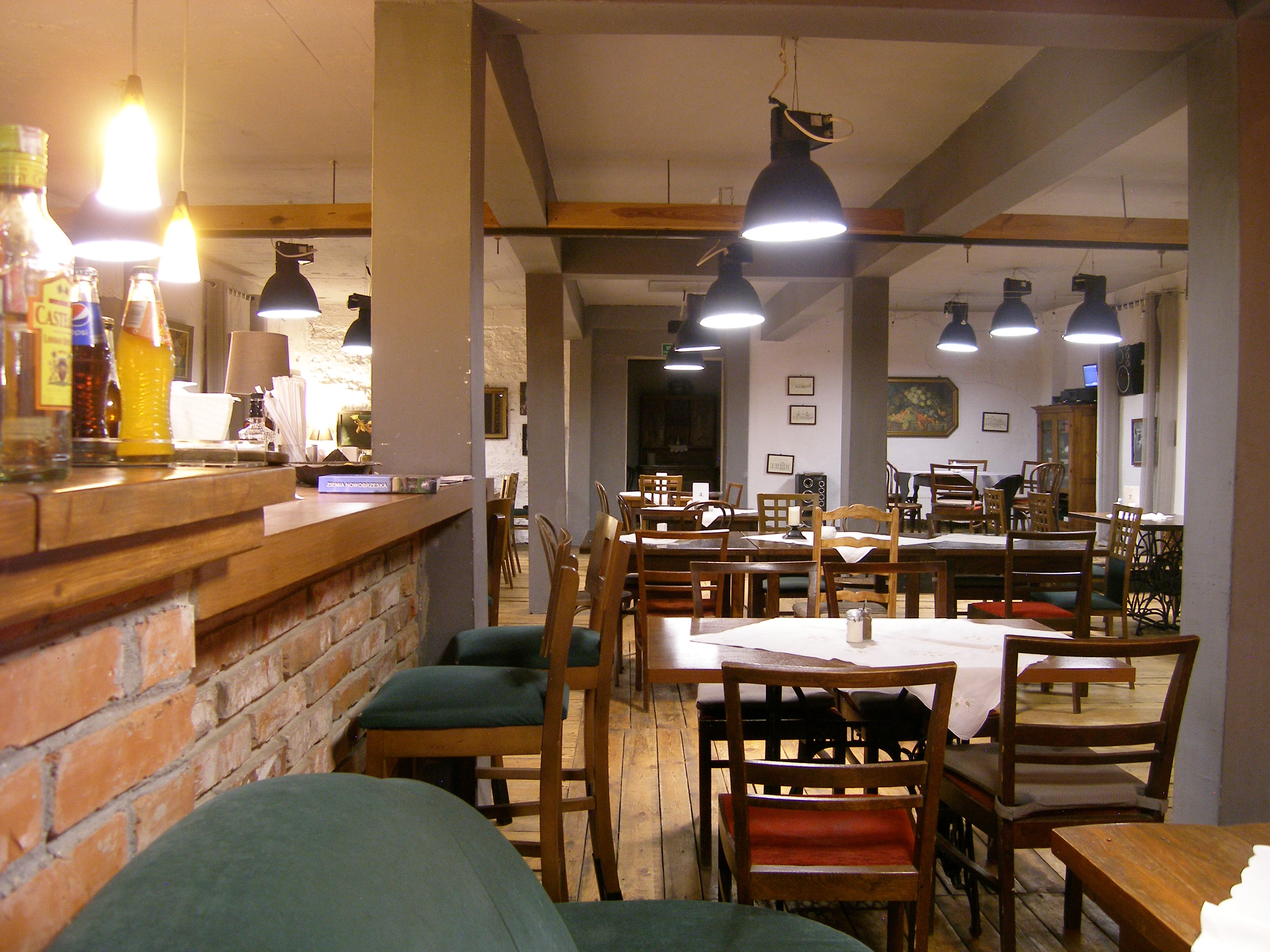 Wnętrze restauracji Stara Stajnia — kuchnia, wino, jazz z drewnianymi stołami i ciepłym światłem